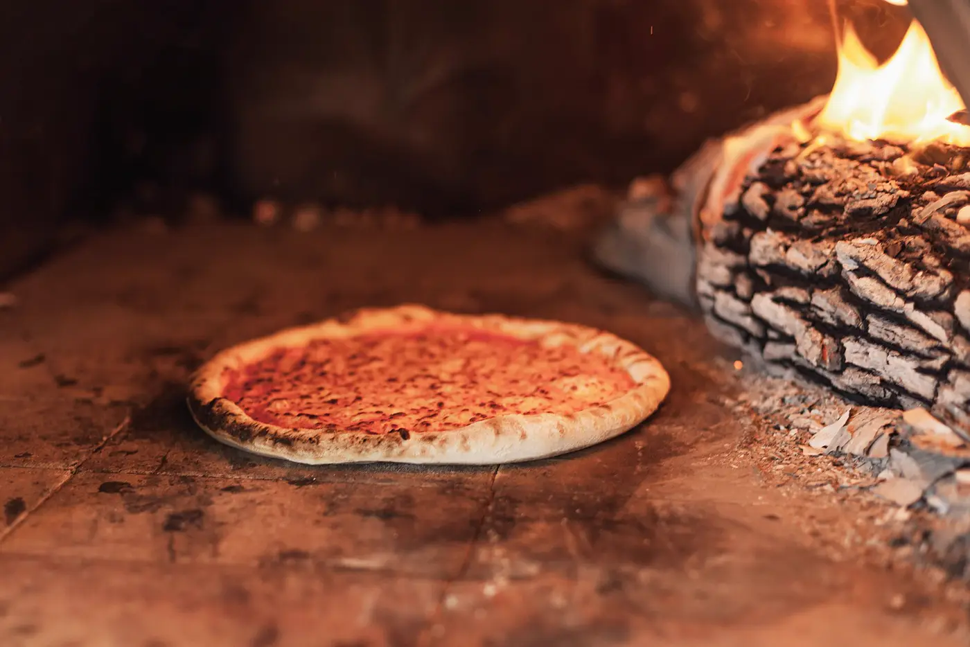 Une pizza enfournée dans un four à bois